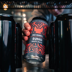 Person holding a can of Mad Squirrel Sumo Hazy Pale Ale with other cans in the background.
